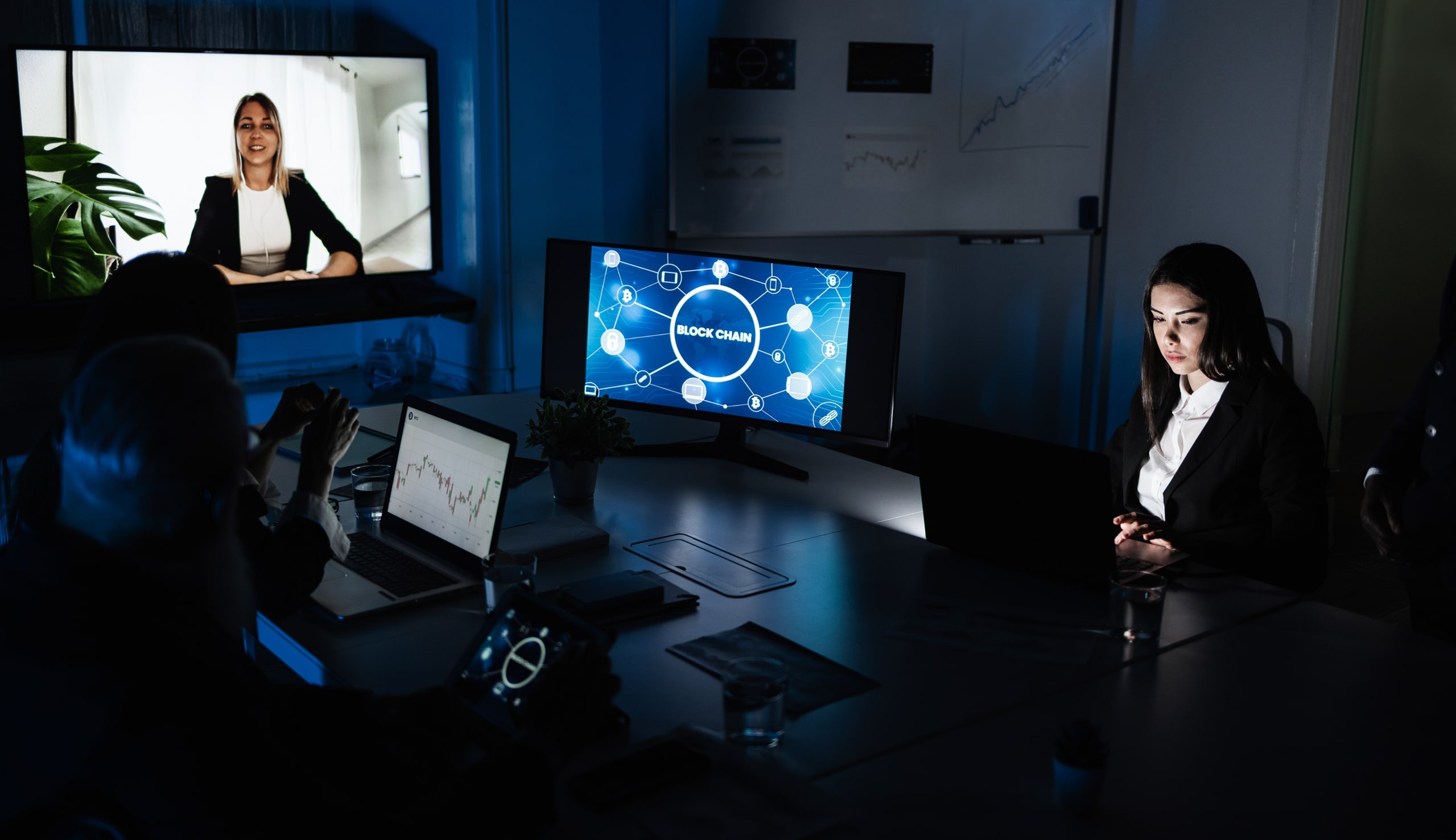 Introducción A La Investigación De Movimientos De Fondos En Entornos Digitales Imagen de una reunión empresarial en la que un equipo analiza gráficos financieros y conceptos de blockchain en pantallas, representando la introducción a la investigación de movimientos de fondos y el análisis de transacciones digitales en un entorno corporativo moderno.