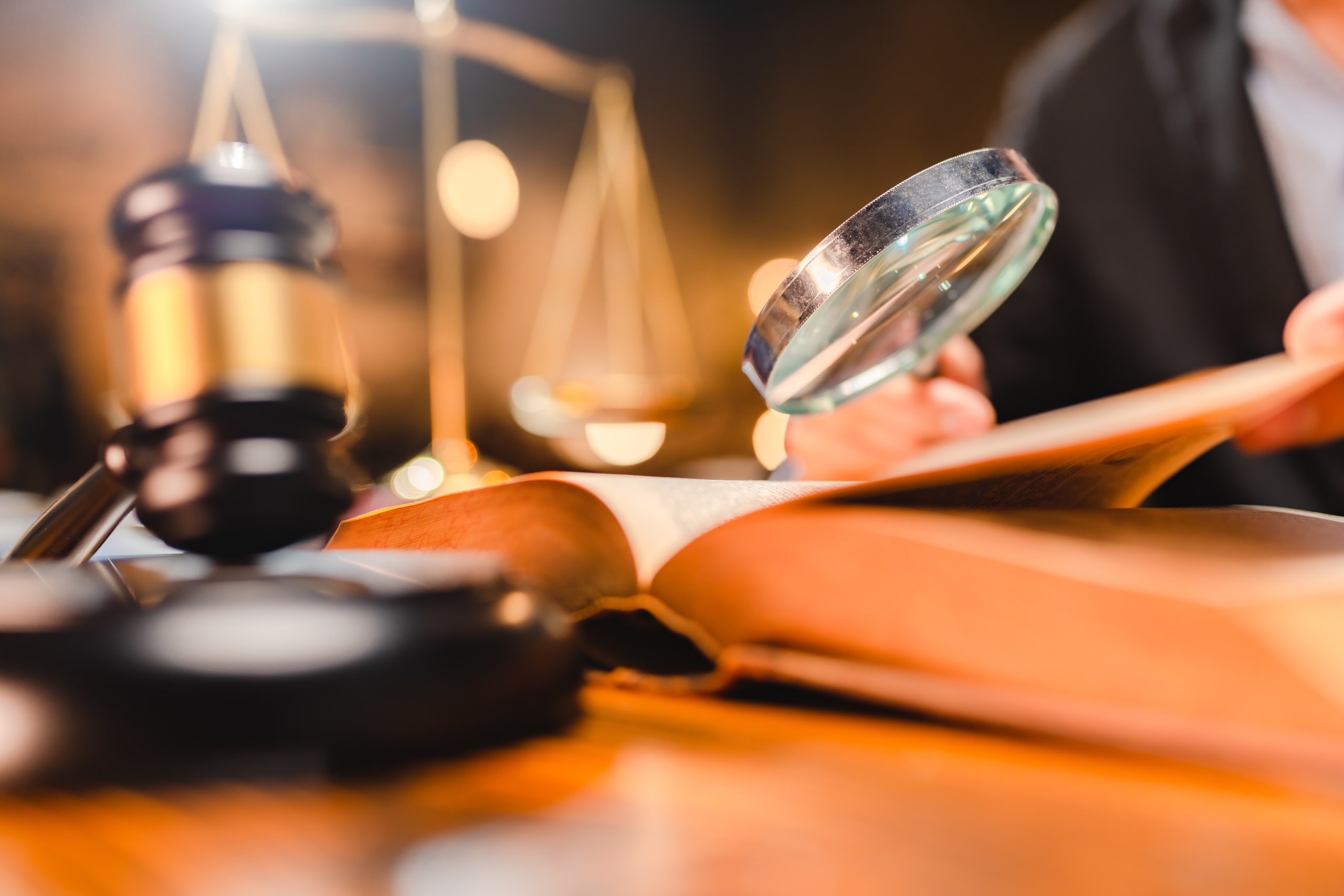 Casos Prácticos De Auditoría Forense Análisis Minucioso De Documentos Legales Imagen que ilustra casos prácticos de auditoría forense, con un juez o abogado examinando detenidamente un libro de leyes con una lupa, junto a un mazo judicial y una balanza de la justicia sobre la mesa, simbolizando la investigación detallada de documentos legales y pruebas.